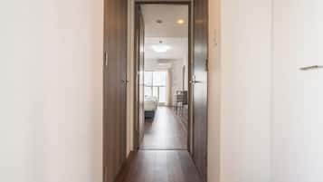 A narrow hallway with wooden doors leading to a room with a bed and a table.