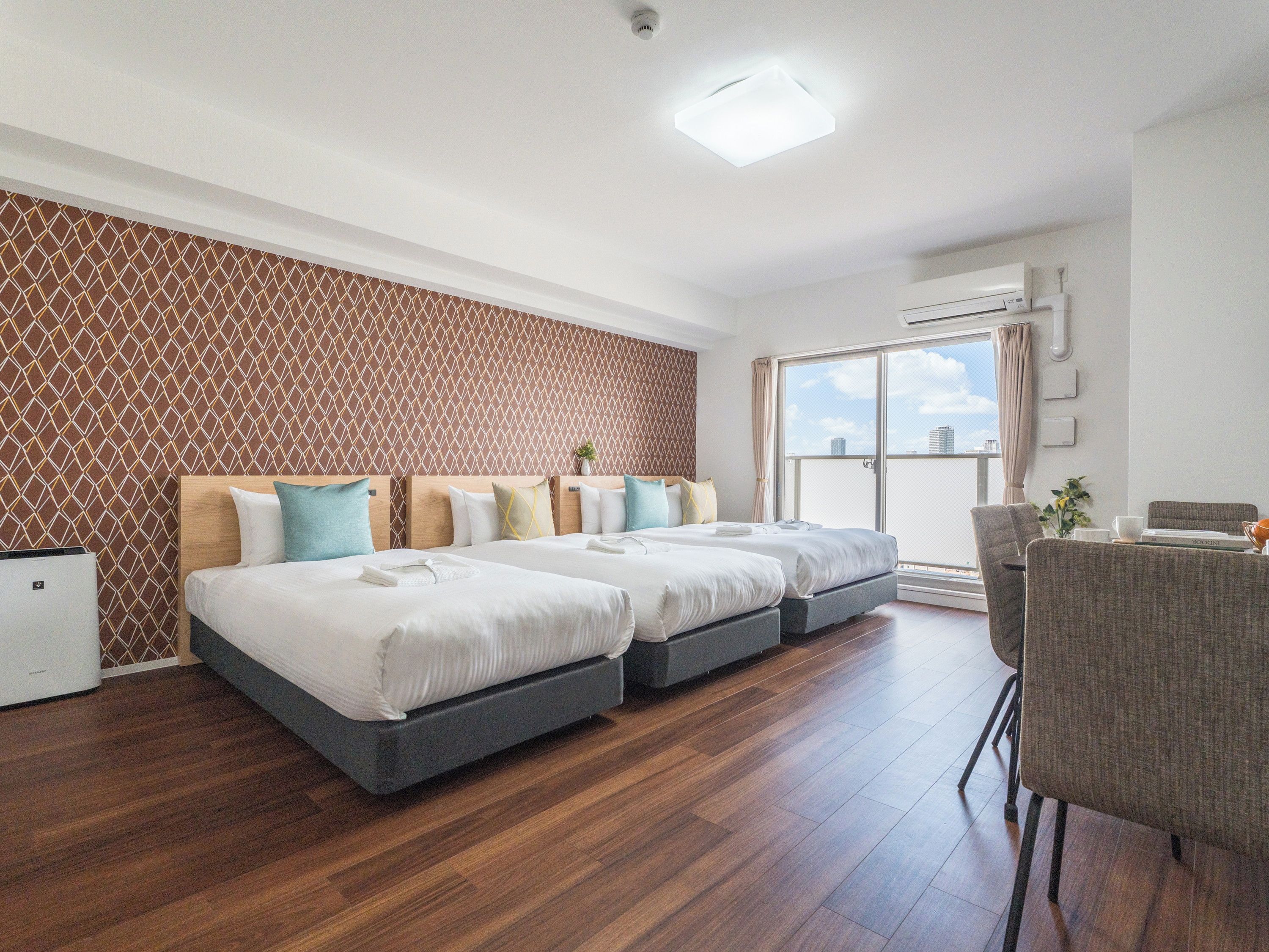 Habitación de hotel con diseño moderno, que incluye una cama grande con varias almohadas, un escritorio pequeño y vistas a través de un ventanal corredero.