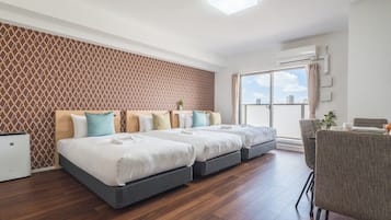 Habitación de hotel con diseño moderno, que incluye una cama grande con varias almohadas, un escritorio pequeño y vistas a través de un ventanal corredero.