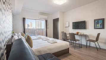 A modern hotel room with a bed, a seating area, and a desk.
