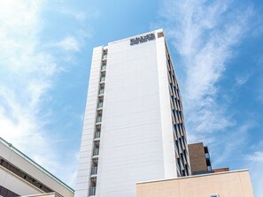 Un hôtel de grande hauteur au design moderne, reconnaissable à son enseigne imposante située en haut de l’édifice.