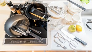 A kitchen with a stove, pots, chopsticks, a cutting board, a knife, scissors, and a plant. - ESLEAD HOTEL Namba Ebisu West (Osaka)
