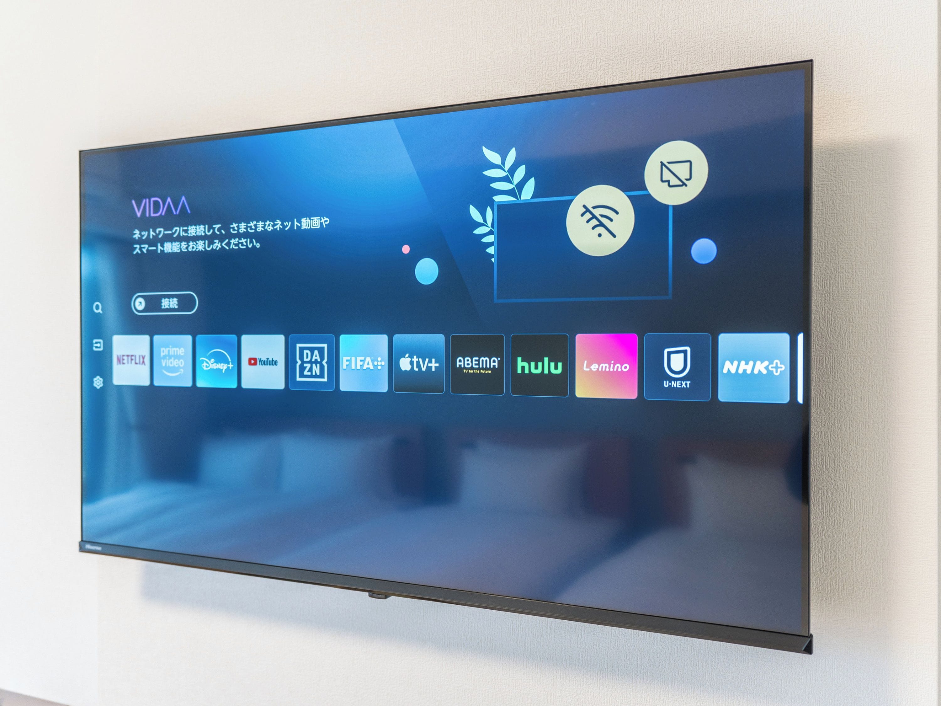 A flat-screen TV mounted on a wall displaying a digital interface with various streaming service icons.