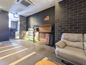 Eine Lobby mit einer Couch, einem Gepäckträger und einem an der Wand befestigten Regal.
