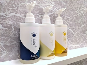 Cuatro botellas de champ ú sobre una repisa frente a una pared de mármol.