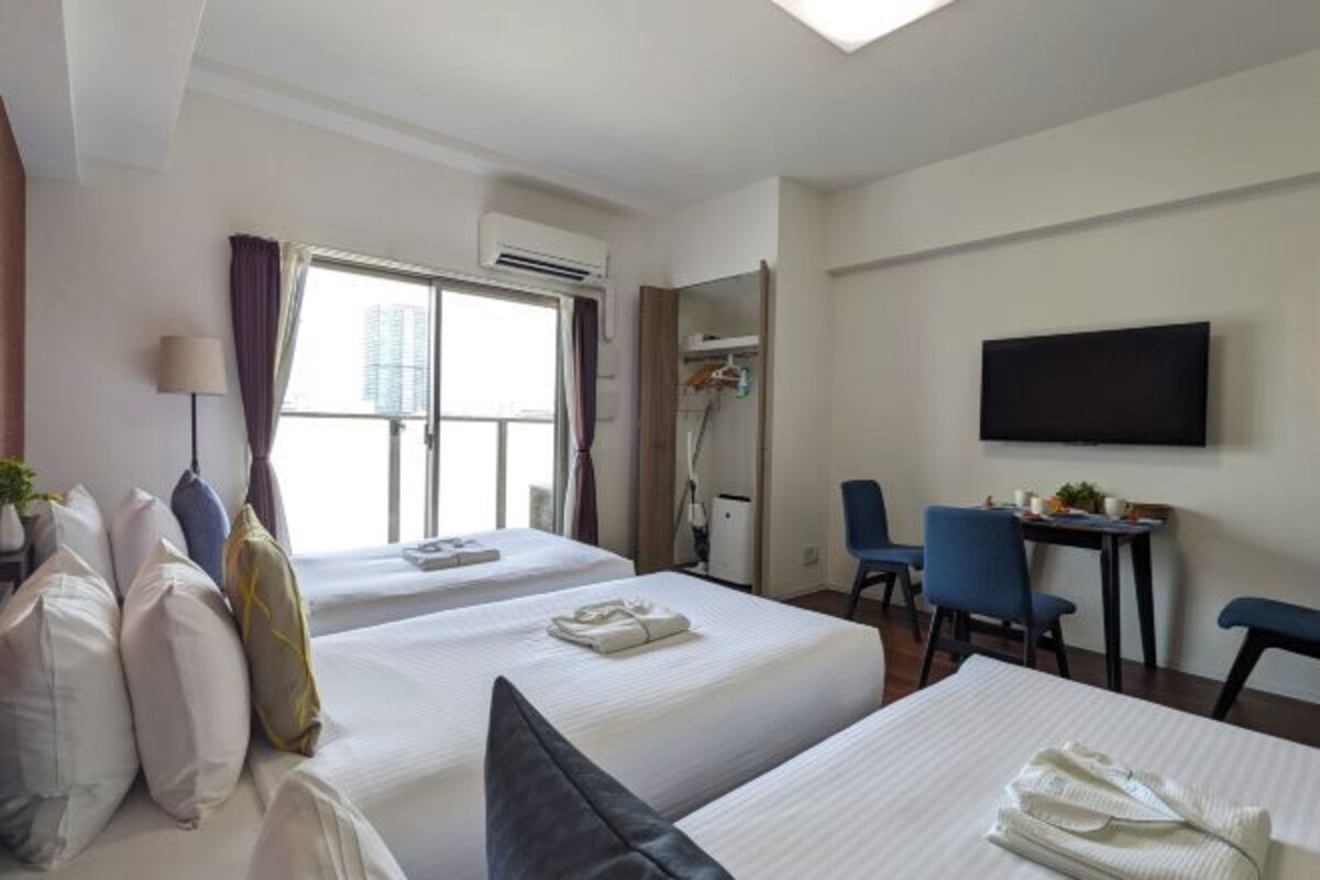 Une chambre d’hôtel avec deux lits, un bureau, une chaise, une télévision et un appareil de climatisation.