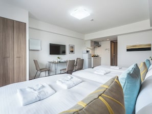 Une chambre d’hôtel avec deux lits, un coin repas, une cuisine et un téléviseur.