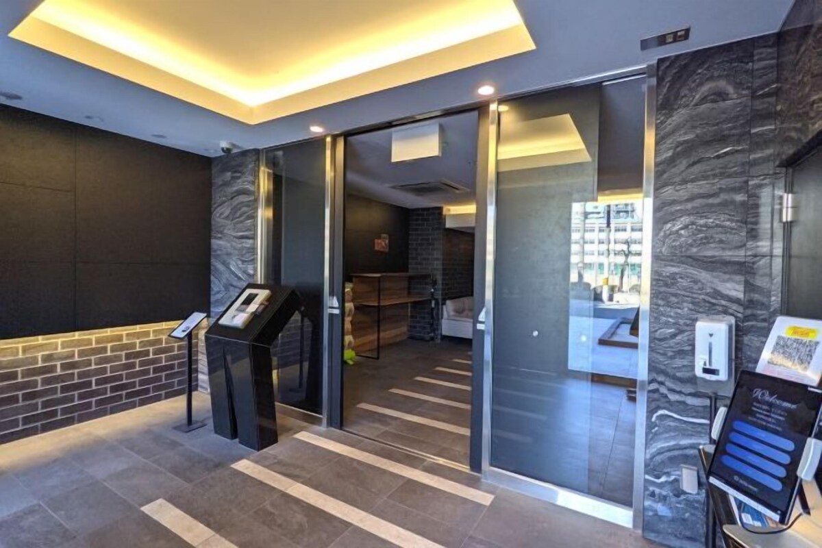 Eine Hotelhalle mit einer Rezeption, einem Glastür-Eingang und einem digitalen Informationsterminal.