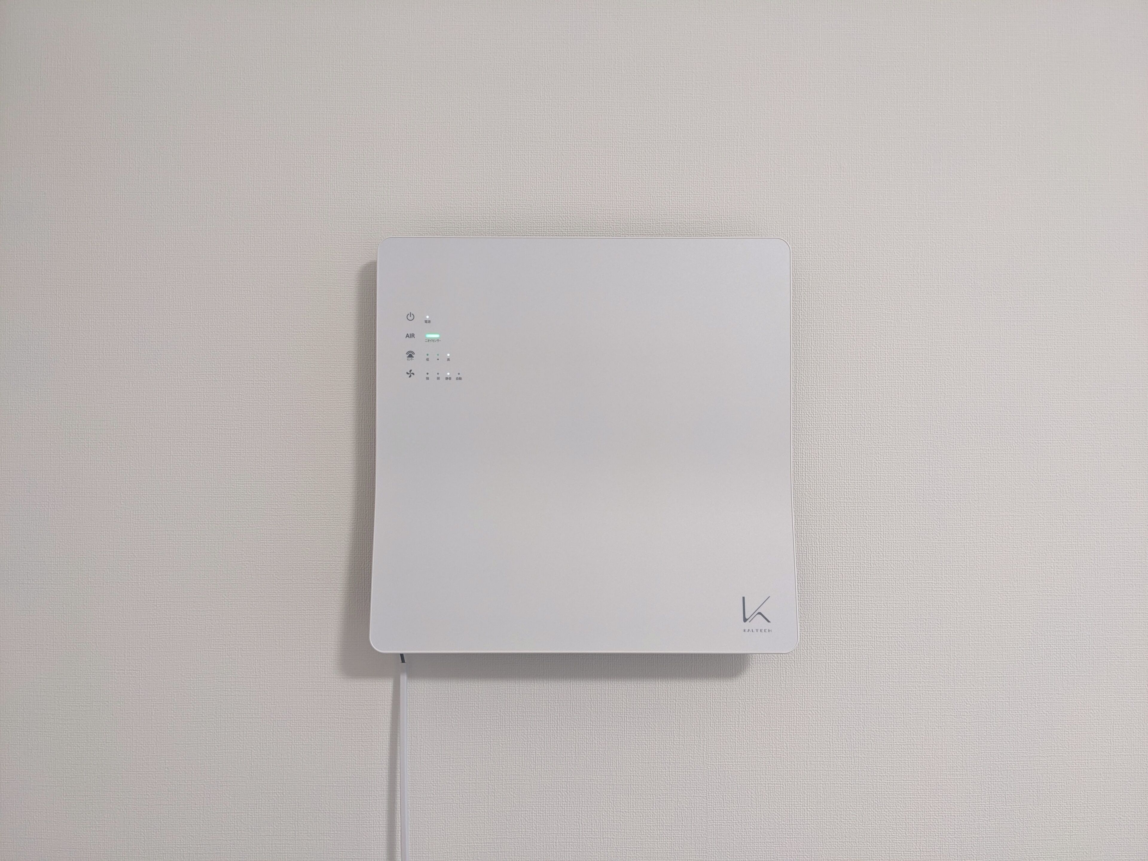Dispositivo electrónico blanco con botón de encendido, sensor de calidad del aire y un logo en la esquina inferior derecha.