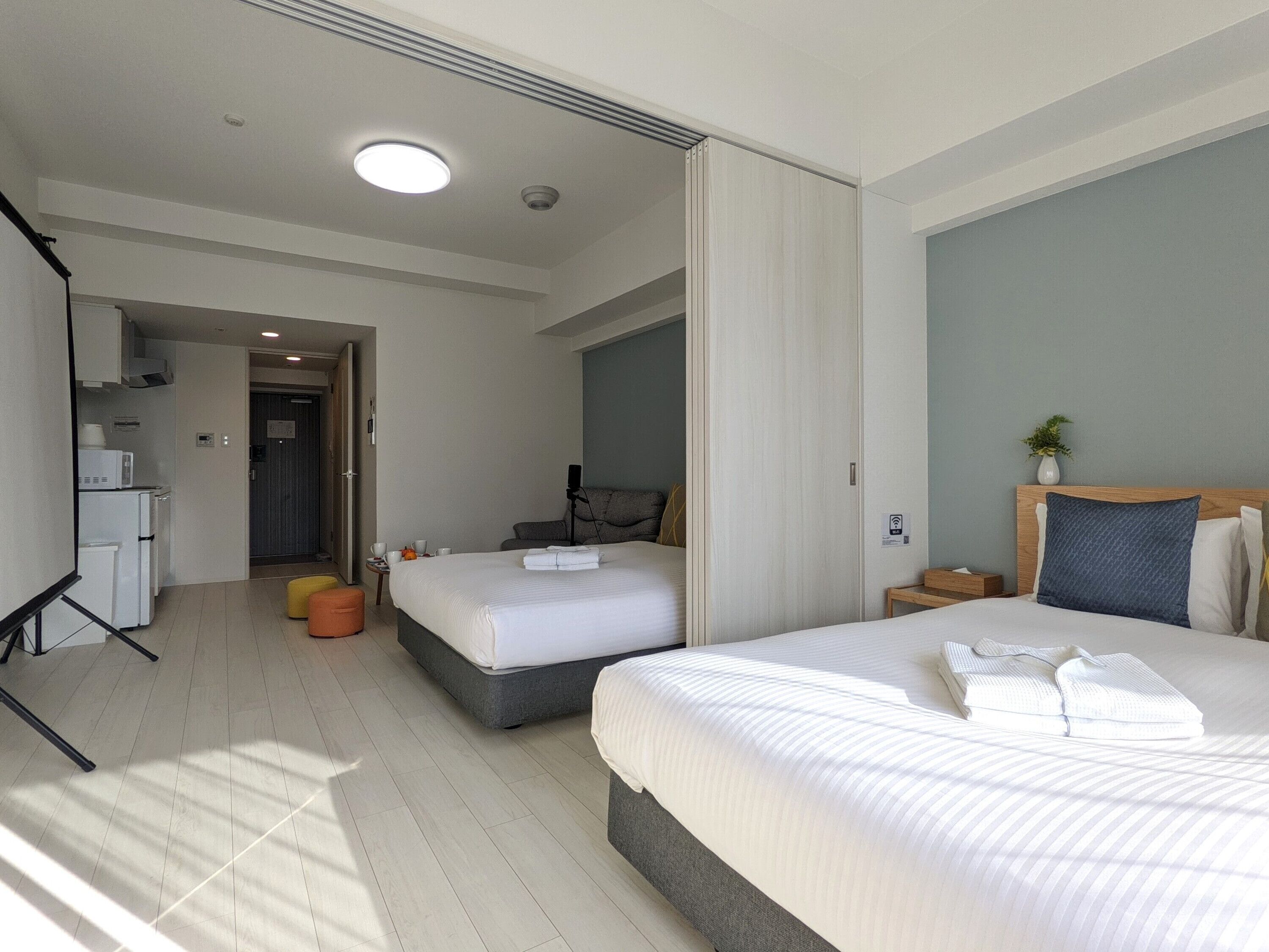 Habitación de hotel con dos camas, kitchenette, zona de estar y baño.