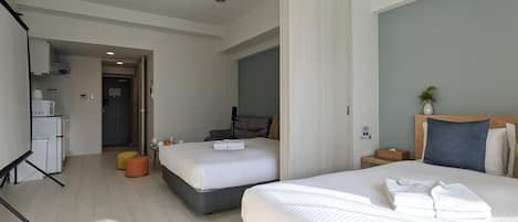 Habitación de hotel con dos camas, kitchenette, zona de estar y baño.
