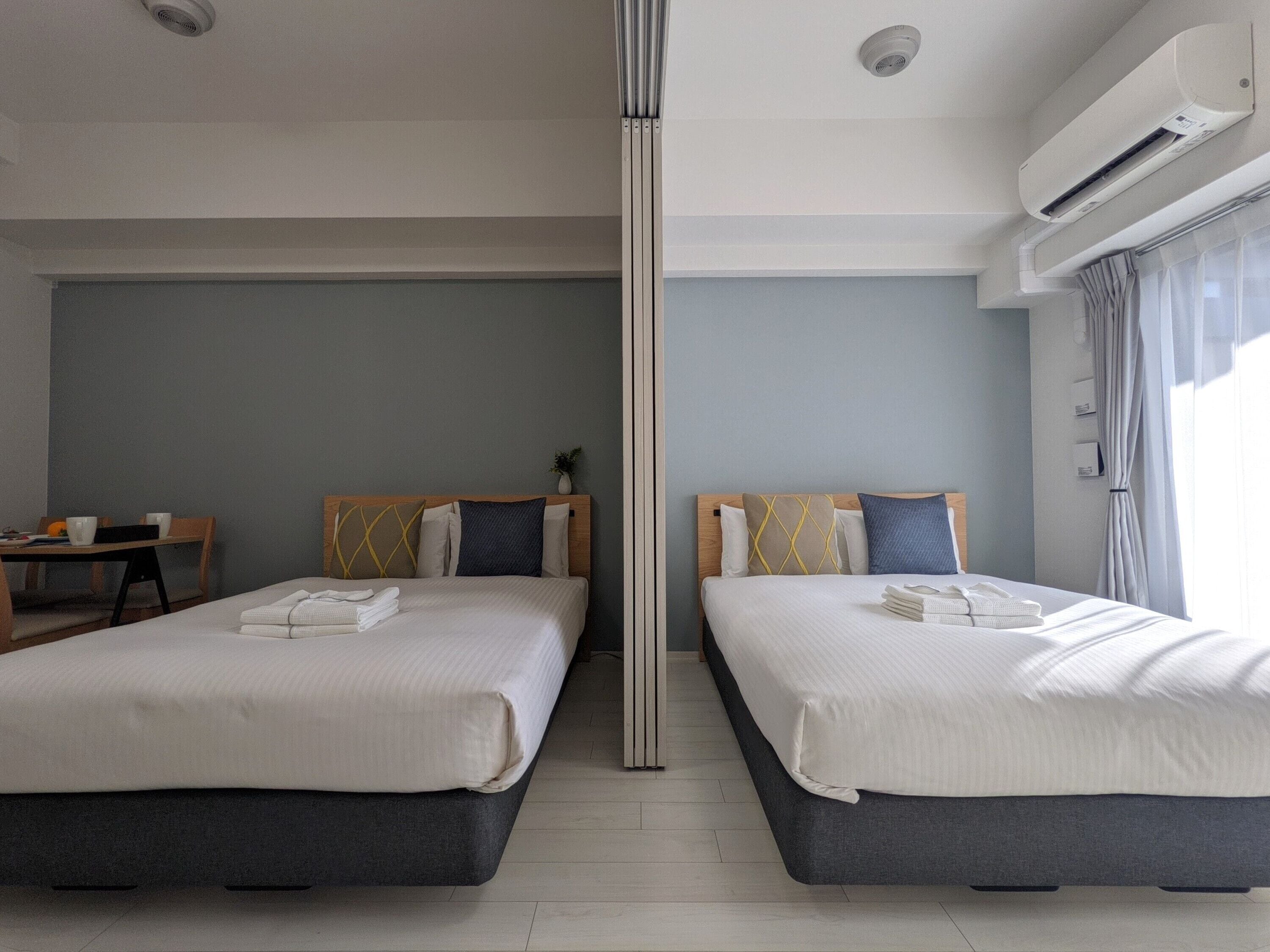 Une chambre d’hôtel avec deux lits, une table et un appareil de climatisation.