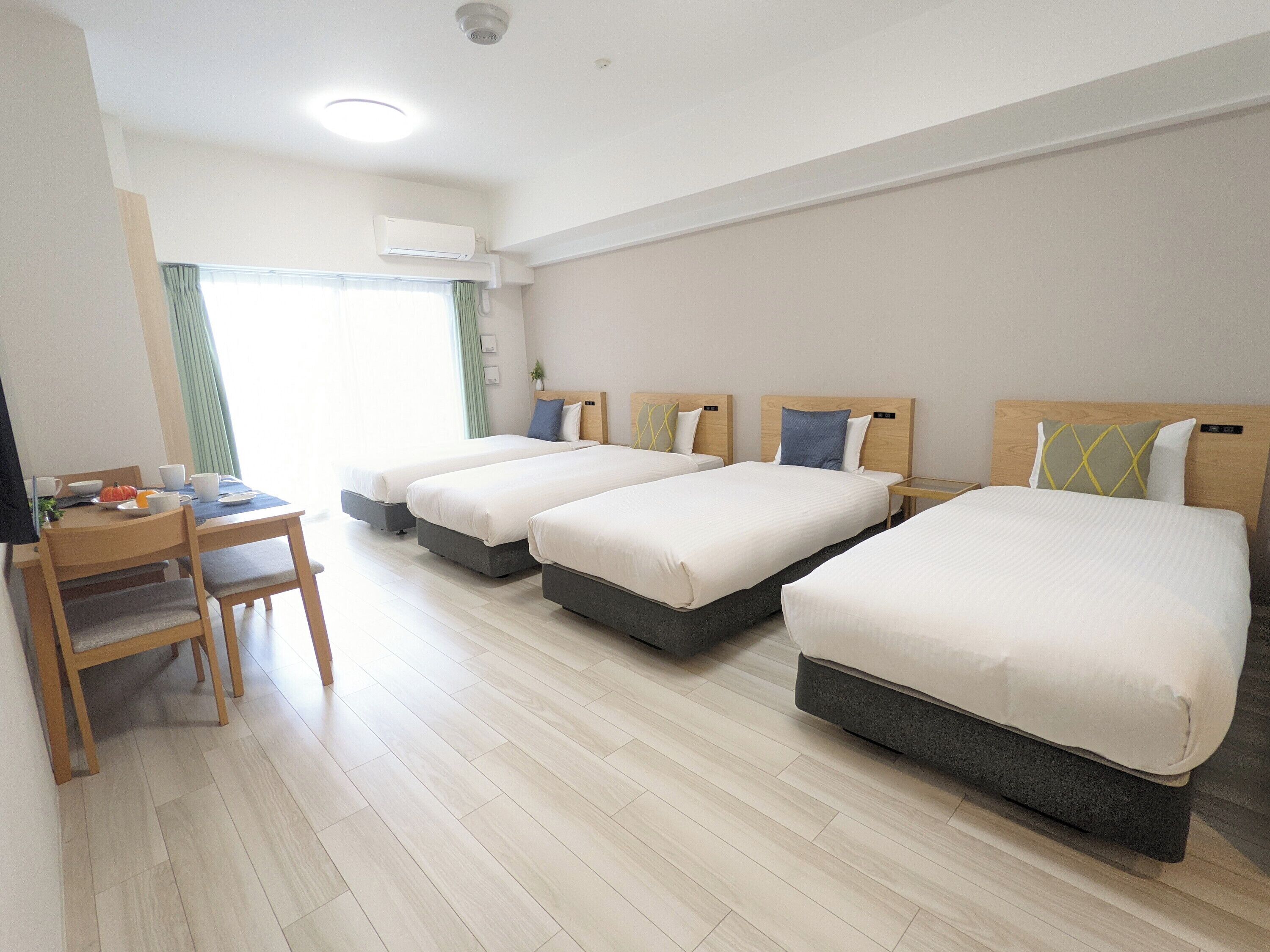 A hotel room with three beds, a desk, and a chair.