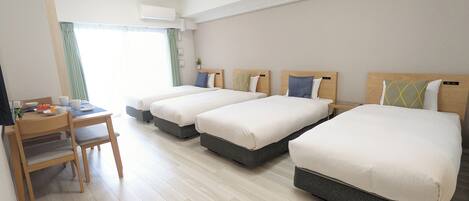 Une chambre d’hôtel avec trois lits, un bureau et une chaise.
