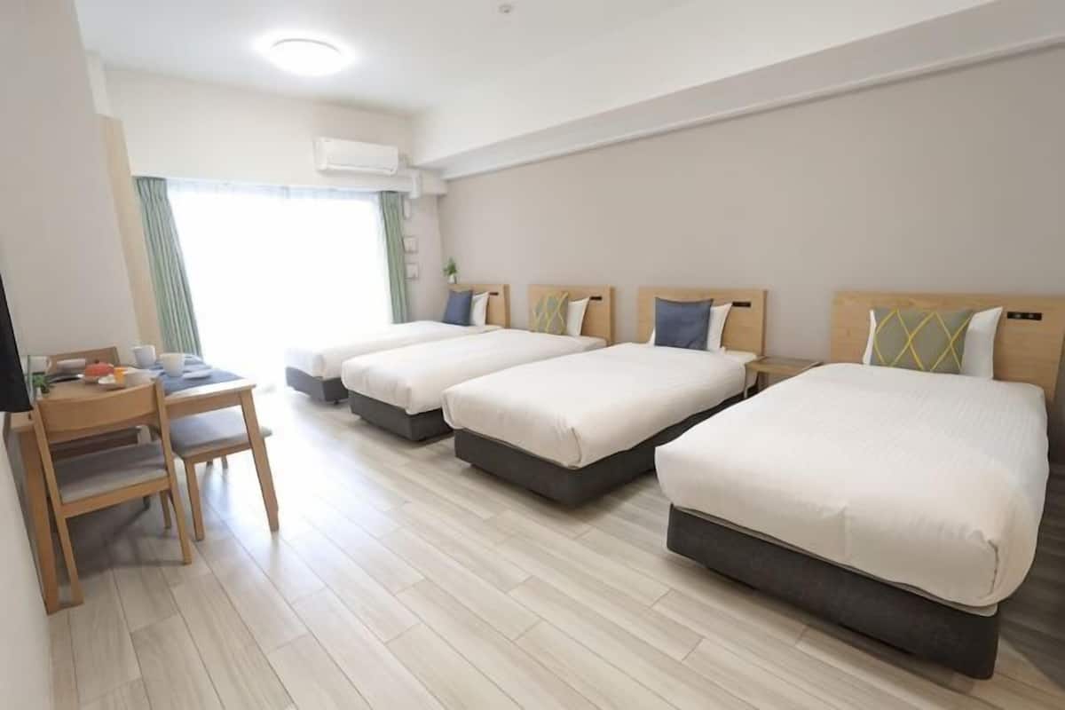 Une chambre dâhĂŽtel avec trois lits, un bureau et une chaise.