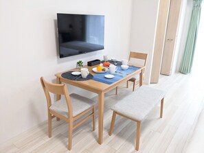 Ein Essbereich mit einem Tisch für vier Personen, einem darüber hängenden Fernseher und einer Tür zu einem anderen Raum.