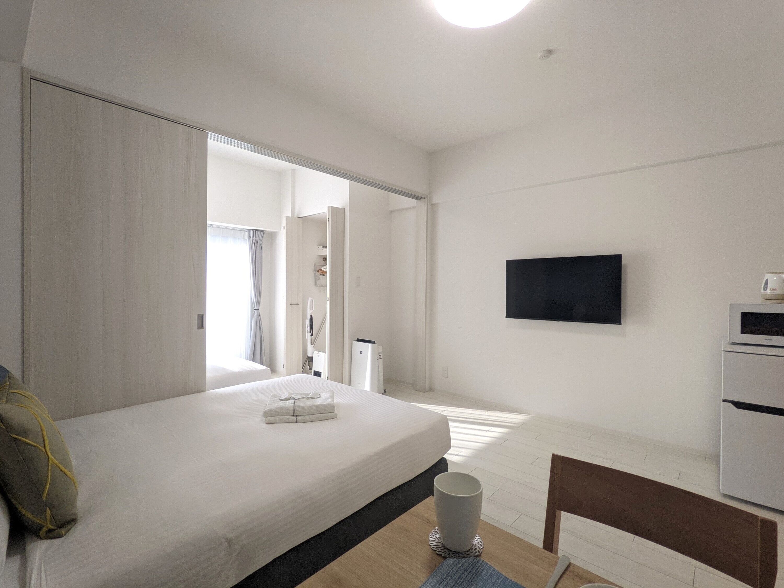 A hotel room with a bed, a flat-screen TV, a microwave, and a small table.