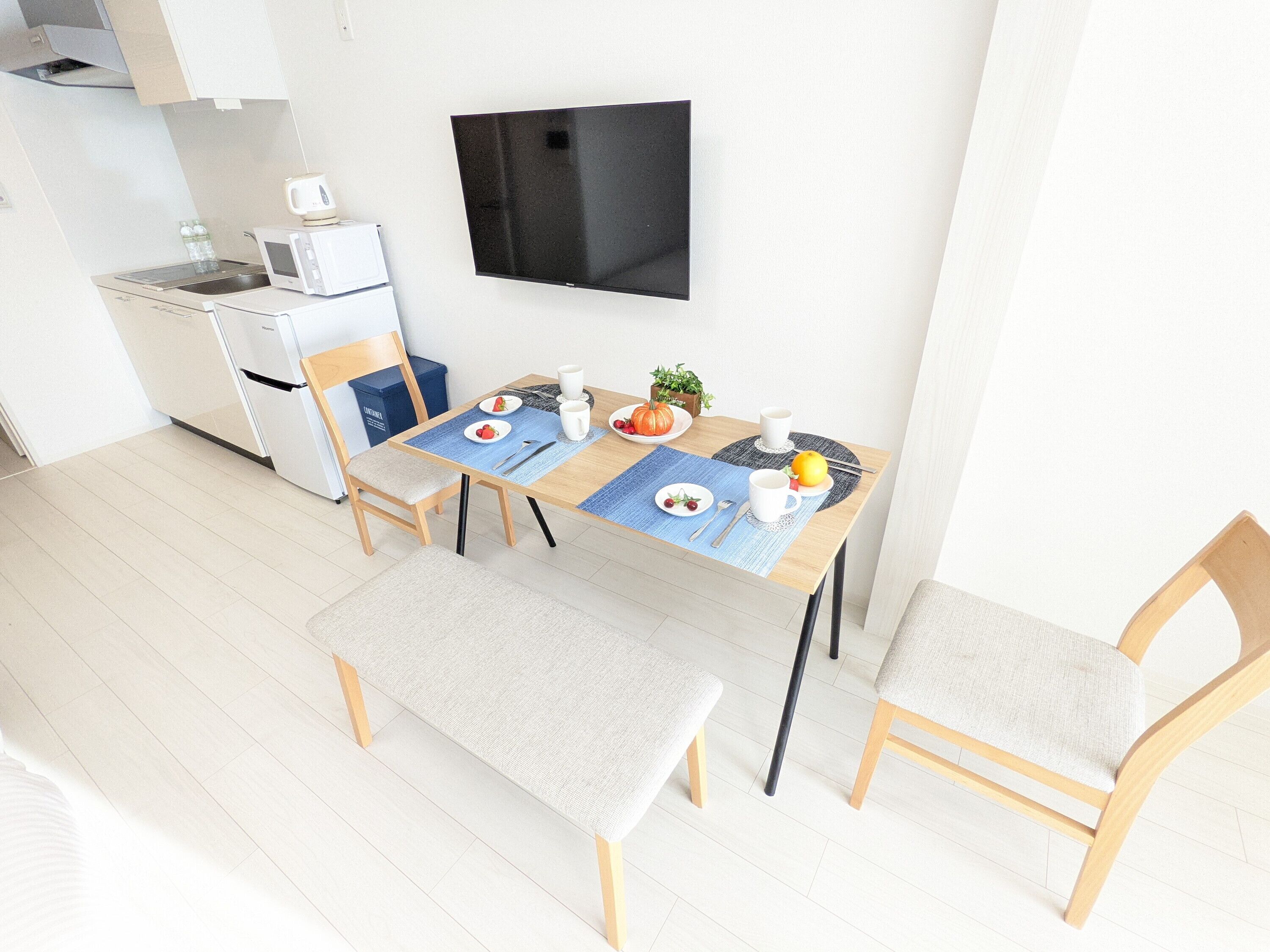 A modern kitchen with a microwave, toaster, and a flat-screen TV on the wall.