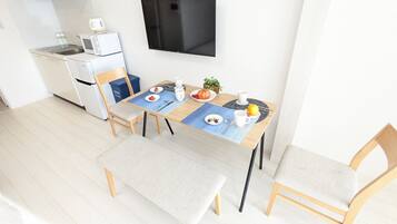 A modern kitchen with a microwave, toaster, and a flat-screen TV on the wall.