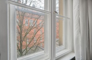 Enjoy a view of the city from this room's window, which offers a glimpse of a nearby red brick building.