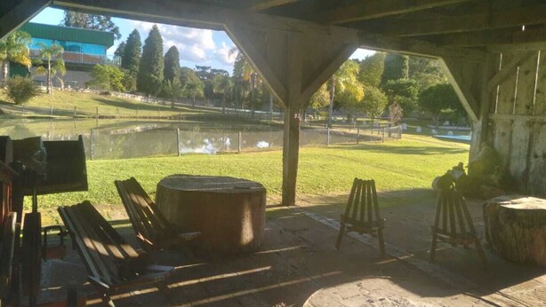 An outdoor seating area with wooden benches and a large tree stump. - Imperial Parque Hotel (Nova Petropolis)