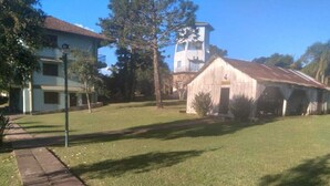 A grassy area with a building, a tower, and a barn. - Imperial Parque Hotel (Nova Petropolis)