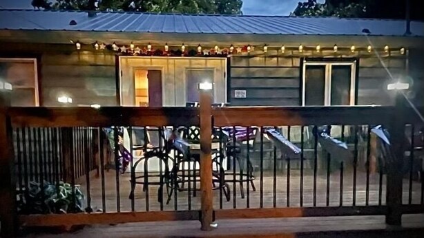 A wooden deck with metal railings, outdoor seating, and string lights. - Checkout this place!! Cindy and Rick will make your stay memorable! (Alma)