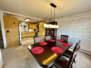 Een eethoek met een lange tafel, zes stoelen en rode placemats.