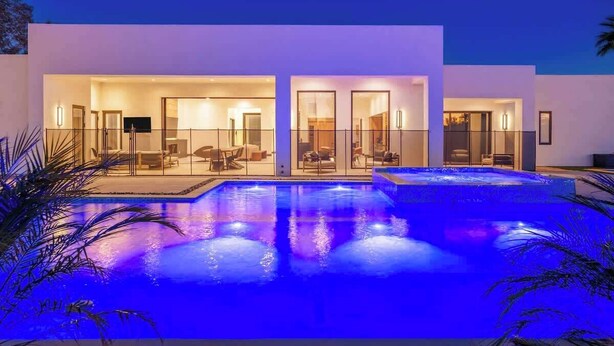 Une maison moderne dotée d’une piscine, de portes vitrées et d’un toit plat.
