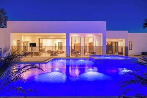 Une maison moderne dotée d’une piscine, de portes vitrées et d’un toit plat.
