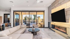 Un salon moderne avec un canapé, une table basse, une cheminée et un téléviseur.