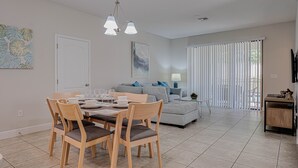 Een moderne woonkamer met een eethoek, met een bank, een salontafel en een eettafel met stoelen.