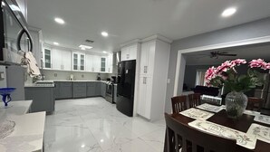 Una cocina moderna con armarios blancos, un refrigerador negro y una zona de comedor con una mesa para dos.