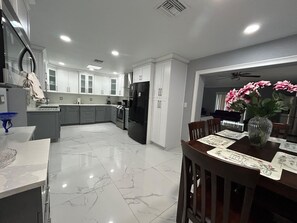 A modern kitchen with white cabinets, a black refrigerator, and a dining area with a table set for two.