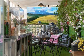 A cozy seating area with a table and chairs, a television displaying a scenic landscape, and a wall adorned with greenery and flowers. - Snowflower Guesthouse  (Seoul)