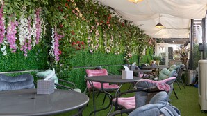 An indoor garden with artificial grass, tables, chairs, and hanging floral decorations. - Snowflower Guesthouse  (Seoul)