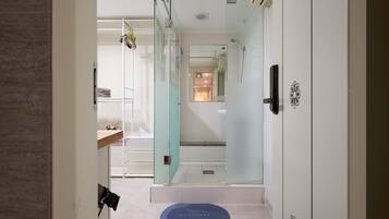 A modern bathroom with a glass shower enclosure, a visible toilet, and a blue mat labeled "BATHROOM" on the floor.