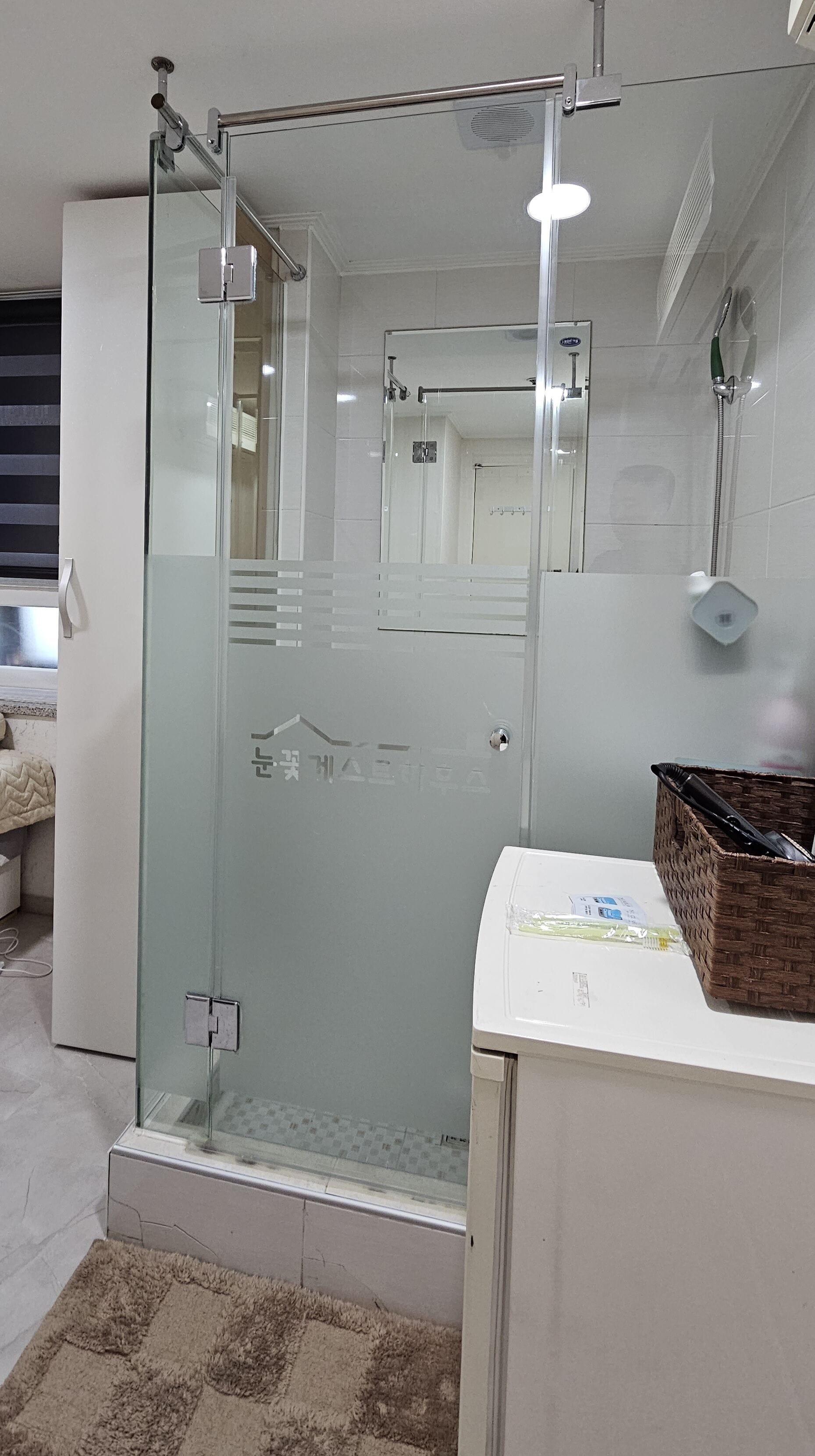 A modern bathroom with a glass shower enclosure, a white sink, and a mirror.
