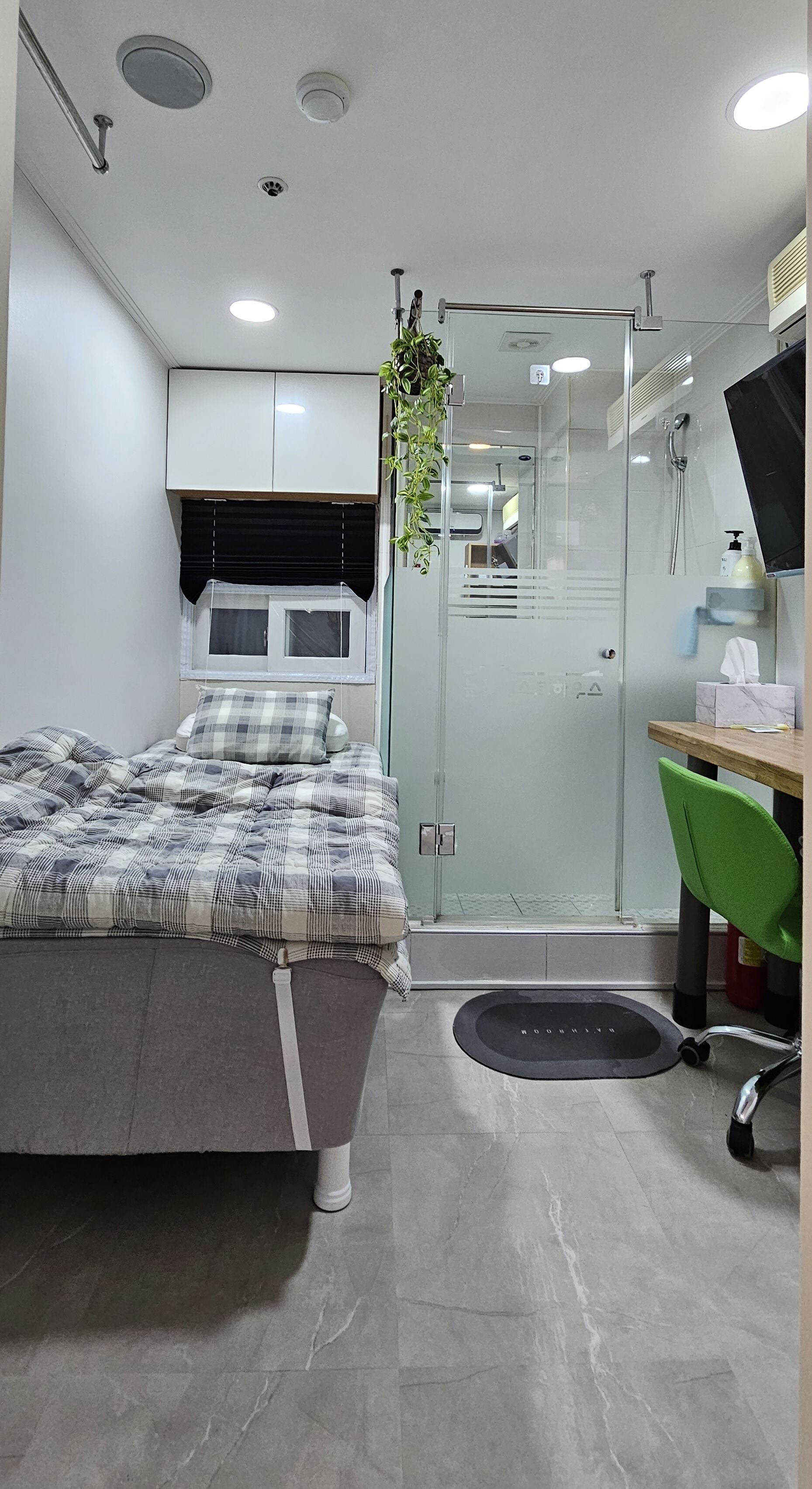 Une chambre à coucher moderne avec un lit, une table de chevet et un fauteuil vert.