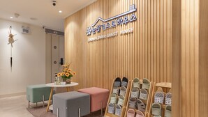 A modern interior with a wooden panel wall, a sign reading "Snowflower Guest House", and a display of slippers. - Snowflower Guesthouse  (Seoul)