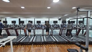 A gym with multiple treadmills, exercise equipment, and large windows offering city views. - Snowflower Guesthouse  (Seoul)
