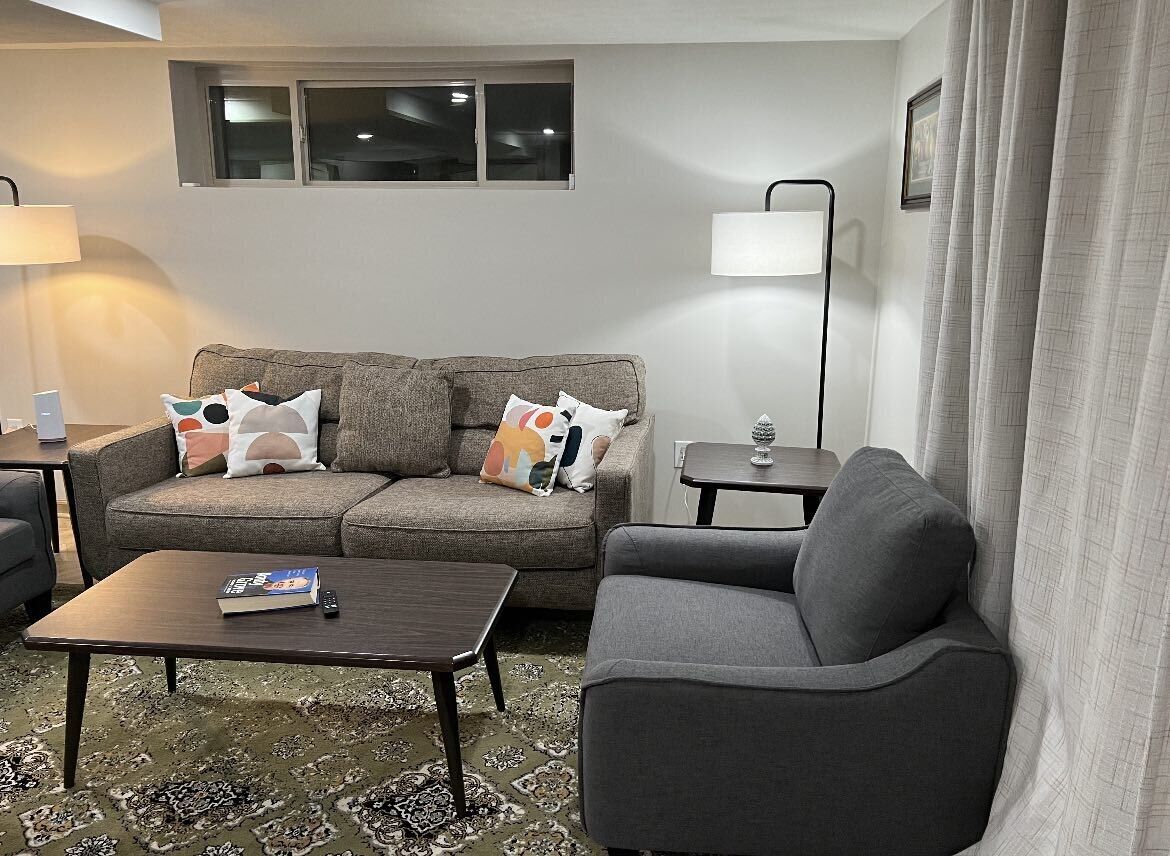 A living room with a sofa, armchair, coffee table, and a lamp.