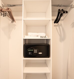 A white wardrobe with a black safe, a hanging shoe rack, and a shelf with folded towels.