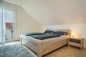 A bedroom with a bed, bedside table, and a view of a balcony. - Holiday Apartment "Haus Barbara, 90 qm' with Private Terrace & Wi-Fi (Lindau am Bodensee)