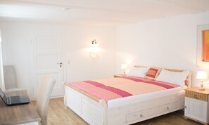 A bedroom with a bed, bedside tables, a chair, and a desk with a laptop. - Holiday Home 'Kleines Landhaus Bodensee' with Lake View, Balcony & Wi-Fi (Überlingen)