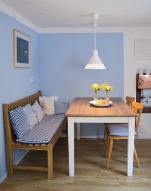 A dining area with a wooden table, a bench, and a hanging light fixture. - Holiday Home 'Kleines Landhaus Bodensee' with Lake View, Balcony & Wi-Fi (Überlingen)