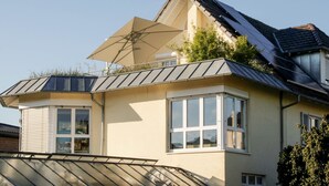 Une maison moderne avec un toit en pente, des panneaux solaires et un grand parasol.