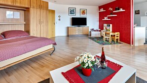 Ein modernes Zimmer mit einem Bett, einem Essbereich, einer Küche und einem Fernseher.