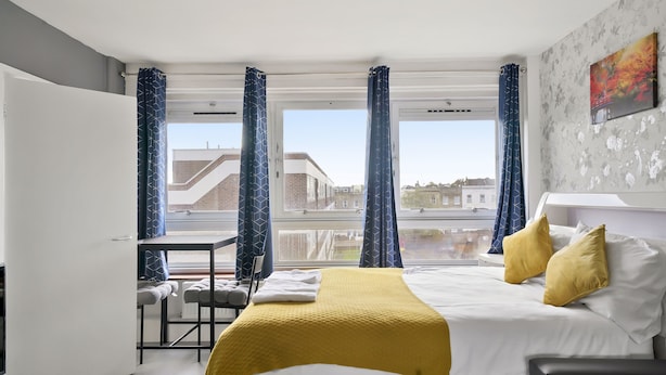 Een moderne hotelkamer met een bed, een bureau en uitzicht op de stad.