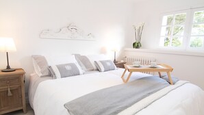 Una camera da letto ordinata con un letto, comodini, un tavolino e una finestra con vista.